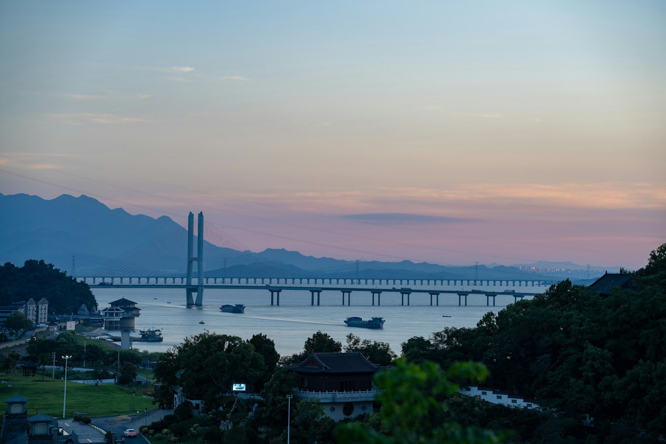 Eine lange Schrägseilbrücke über einem Fluss in der Abenddämmerung