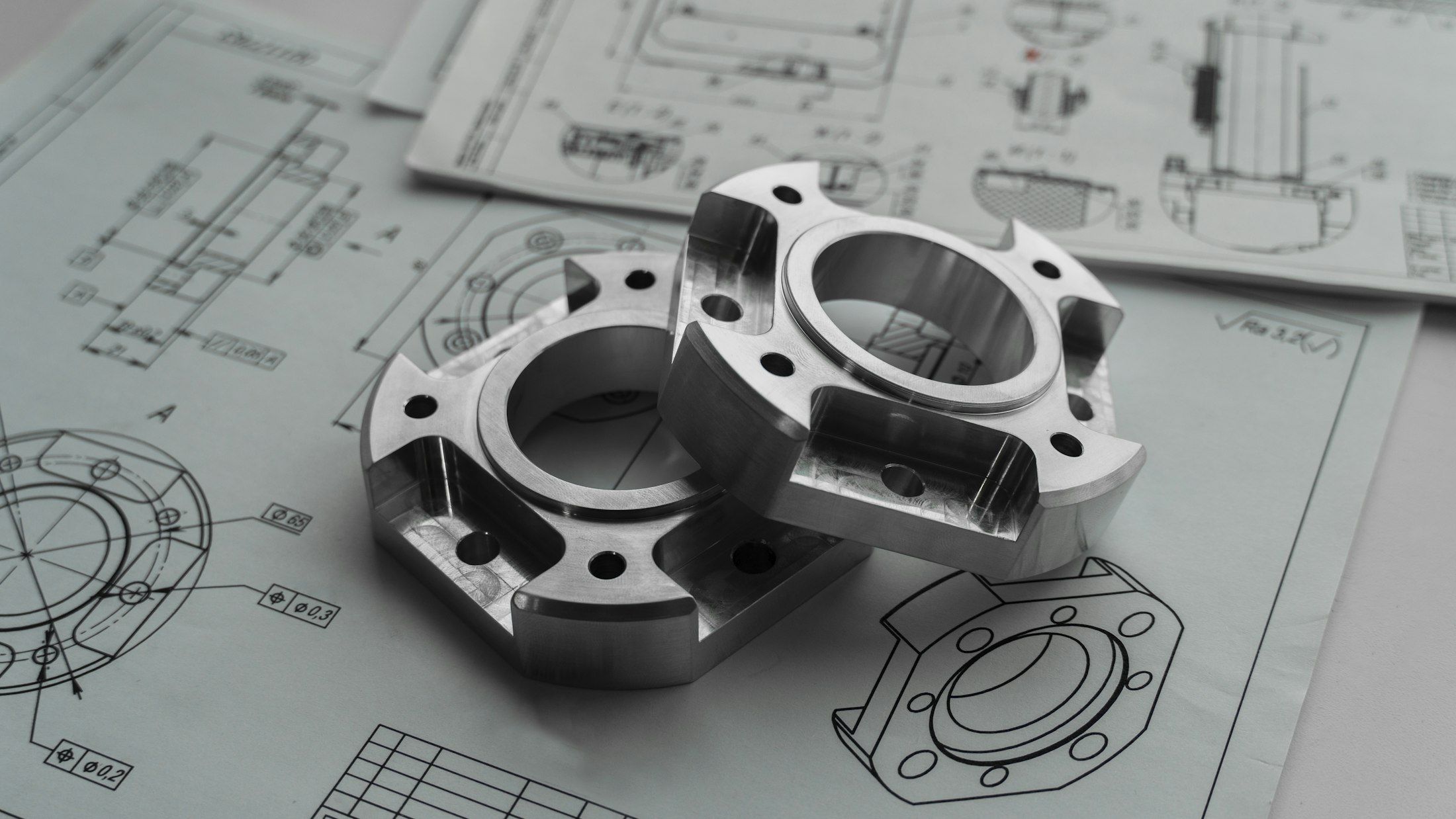 Zwei präzise bearbeitete Metallteile auf technischen Zeichnungen