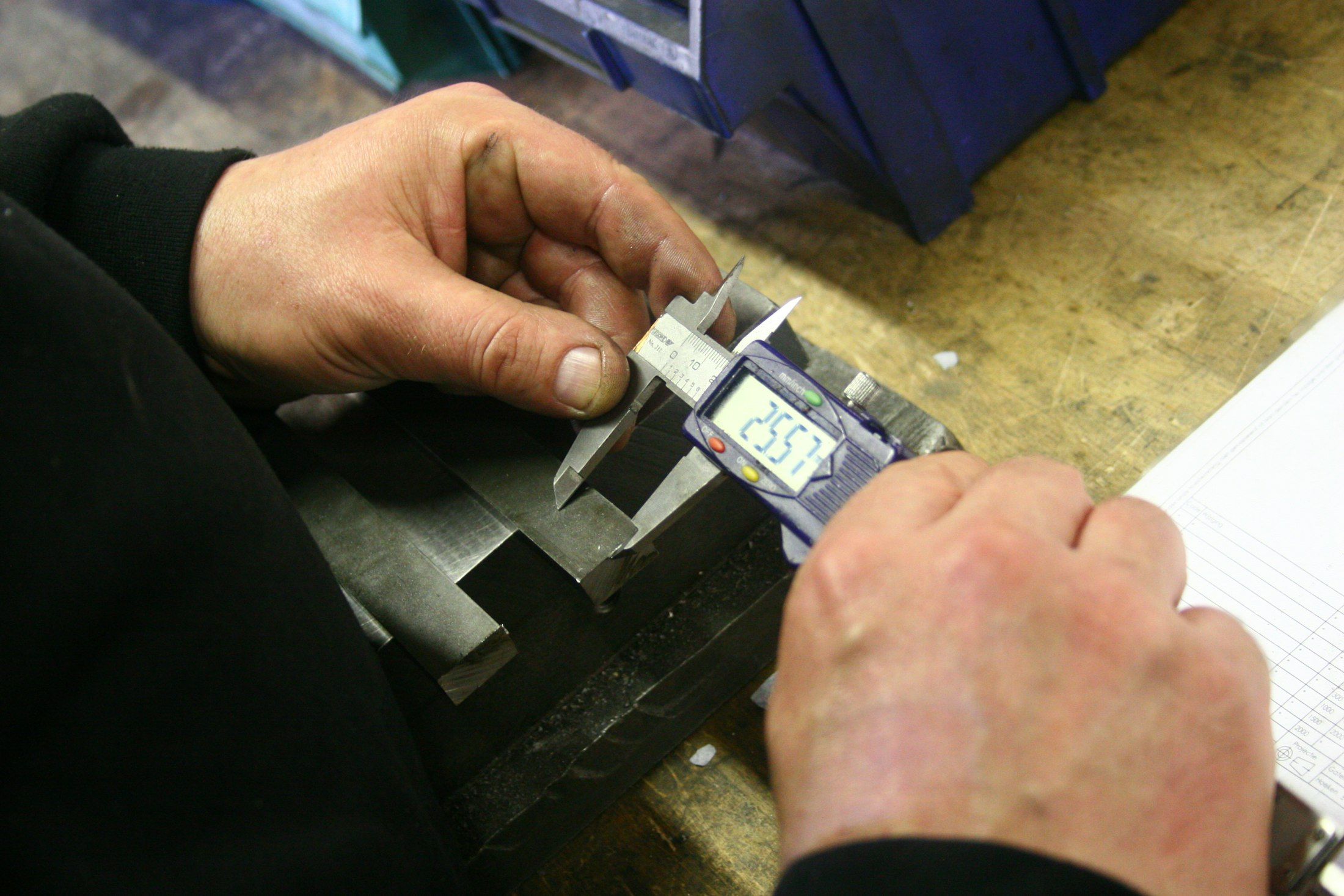 Hände messen ein Drehteil mit einem digitalen Messschieber