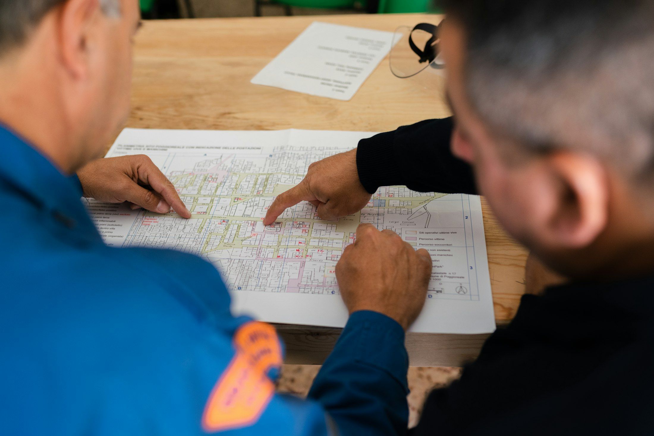 Zwei Ingenieure in Arbeitskleidung besprechen ausgedruckte Pläne