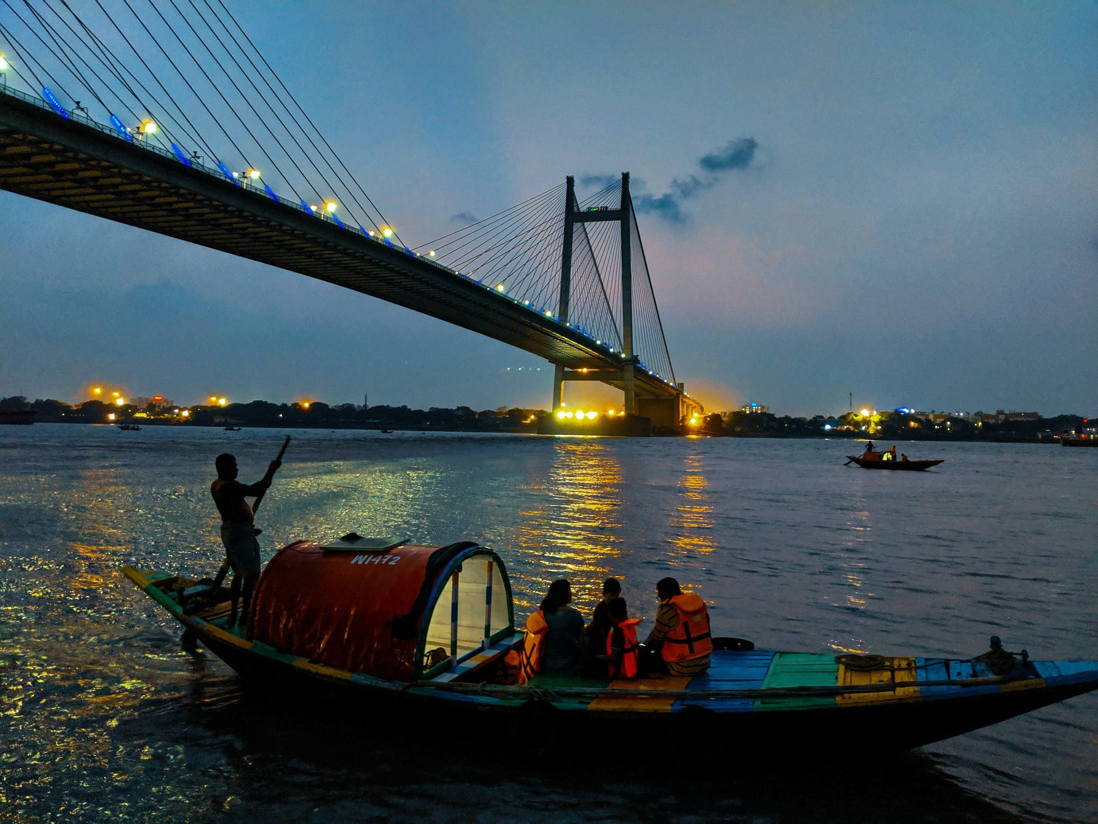 Ein Holzboot auf dem Hooghly, dem Ganges bei Kolkata, unter der Schrägseilbrücke Vidyasagar Setu